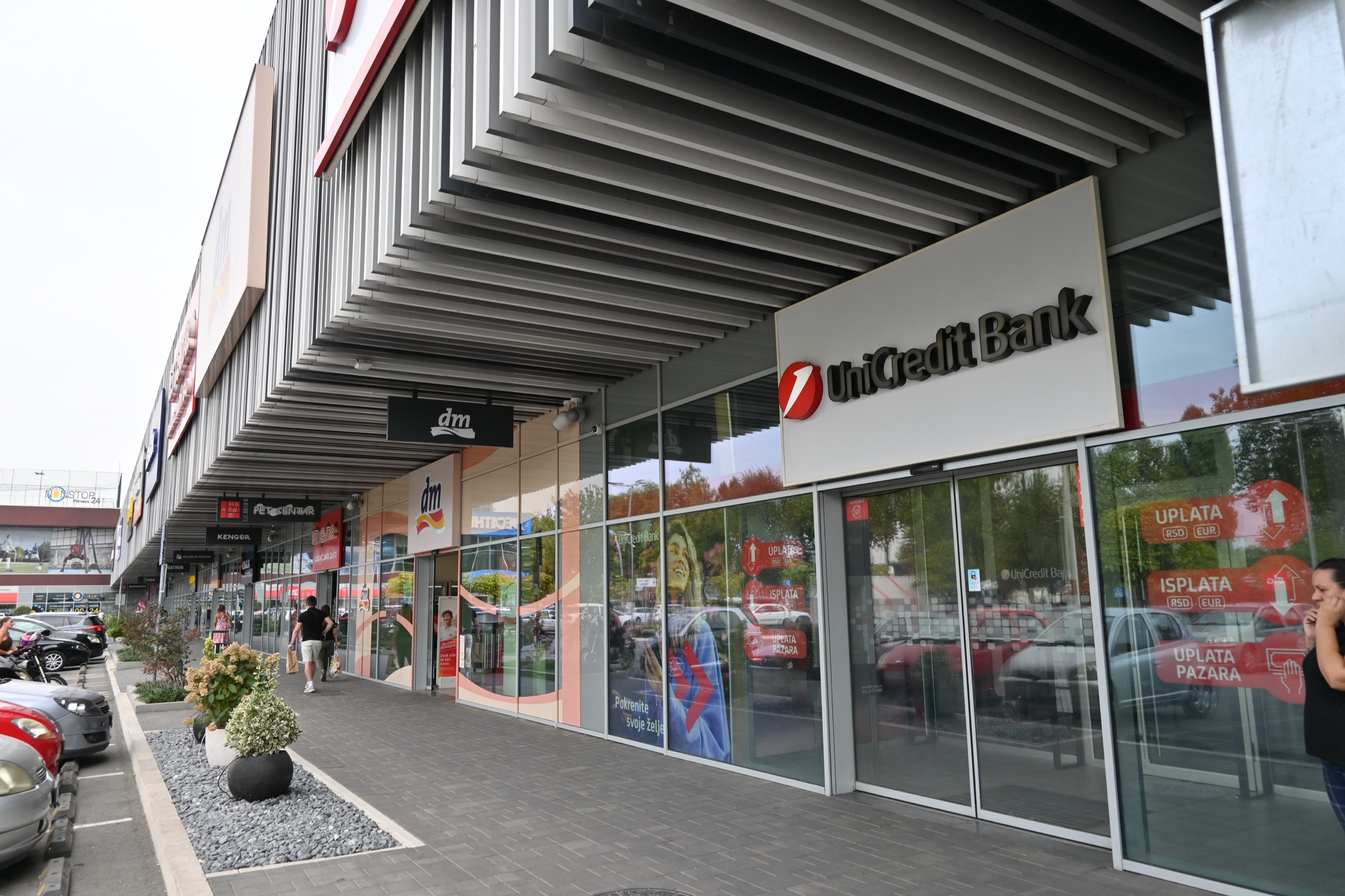 BIG Fashion Park — staklena vrata i izlozi banke i drogerije pod lamelastim krovom