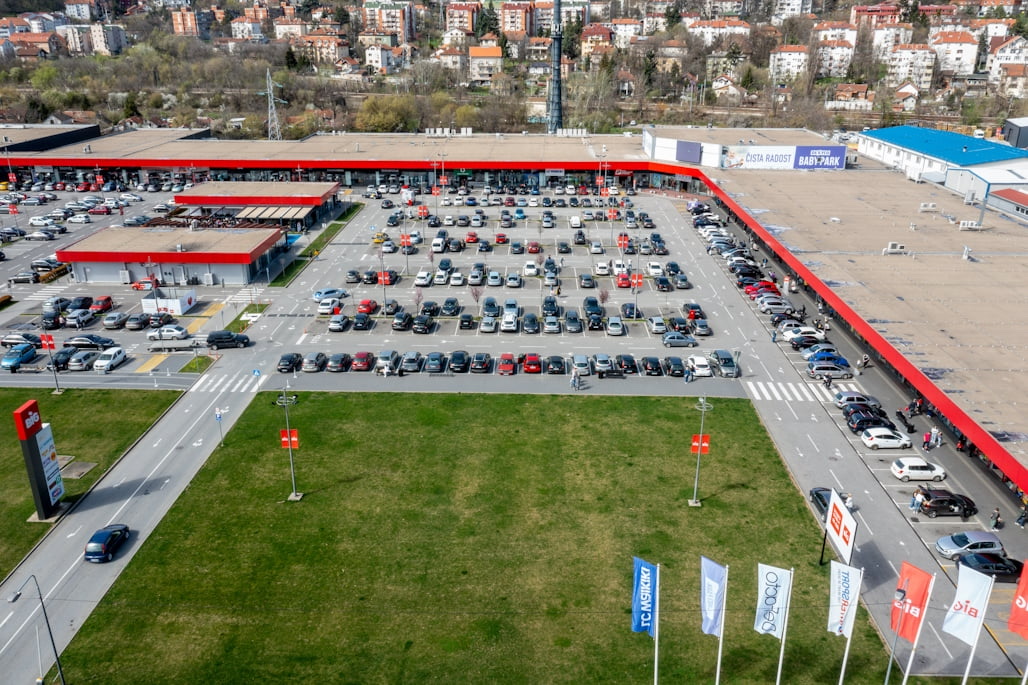 BIG Rakovica — tržni centar iz vazduha: niz prodavnica sa crvenom nadstrešnicom oko parkinga