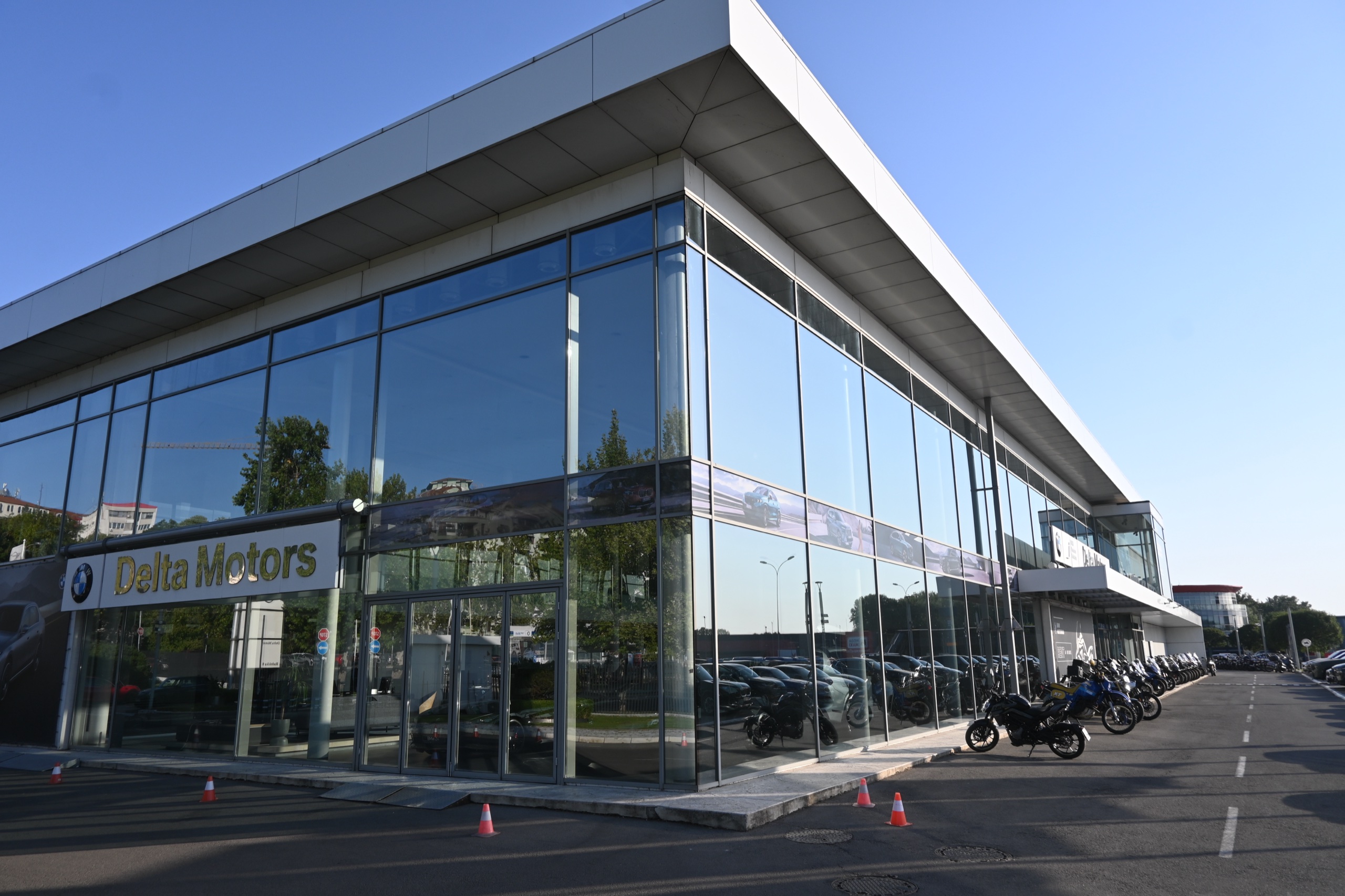 Auto salon BMW & MINI — ugao staklene fasade sa belim krovom i ulaznim vratima
