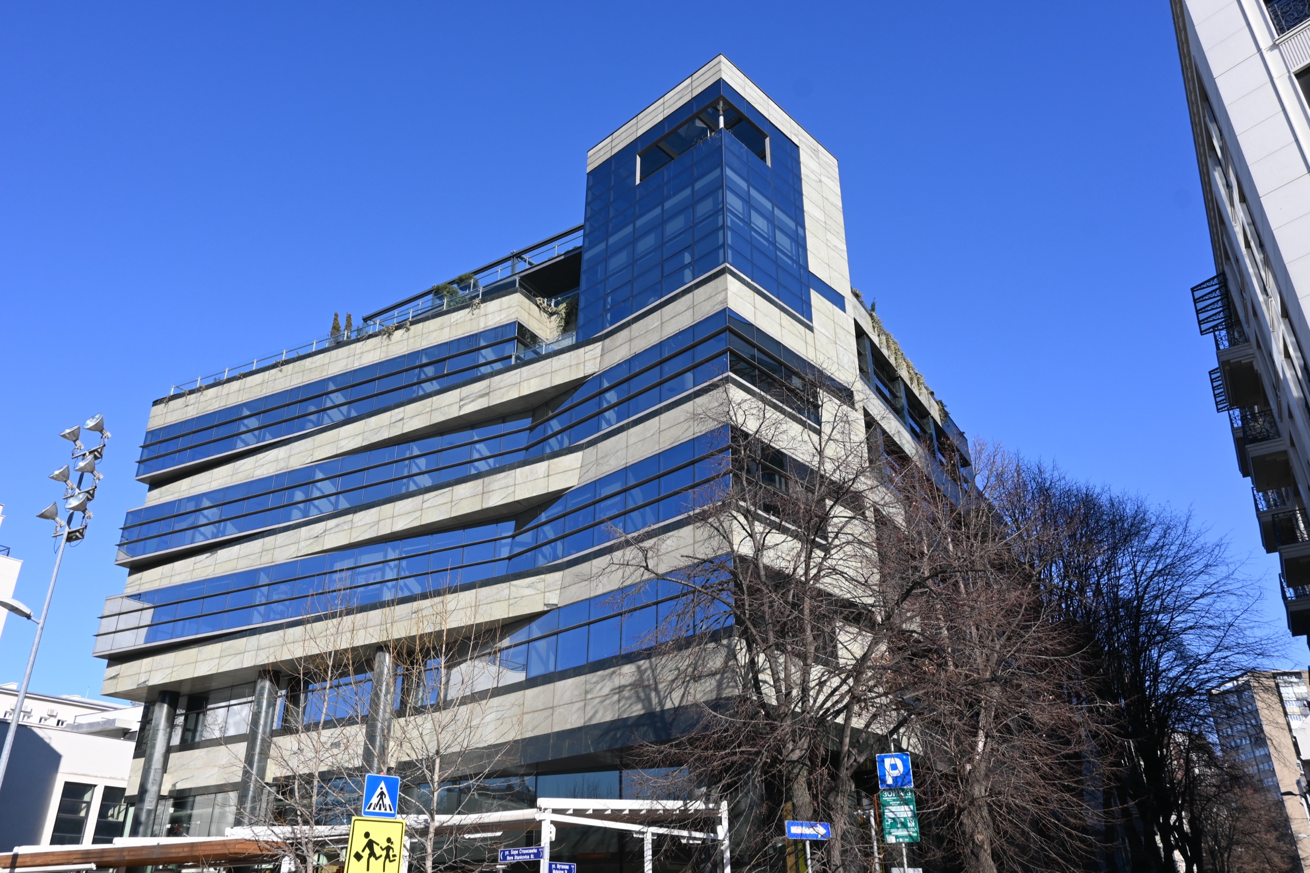 Green Square — staklena ugaona kula i horizontalne trake fasade, pogled odozdo
