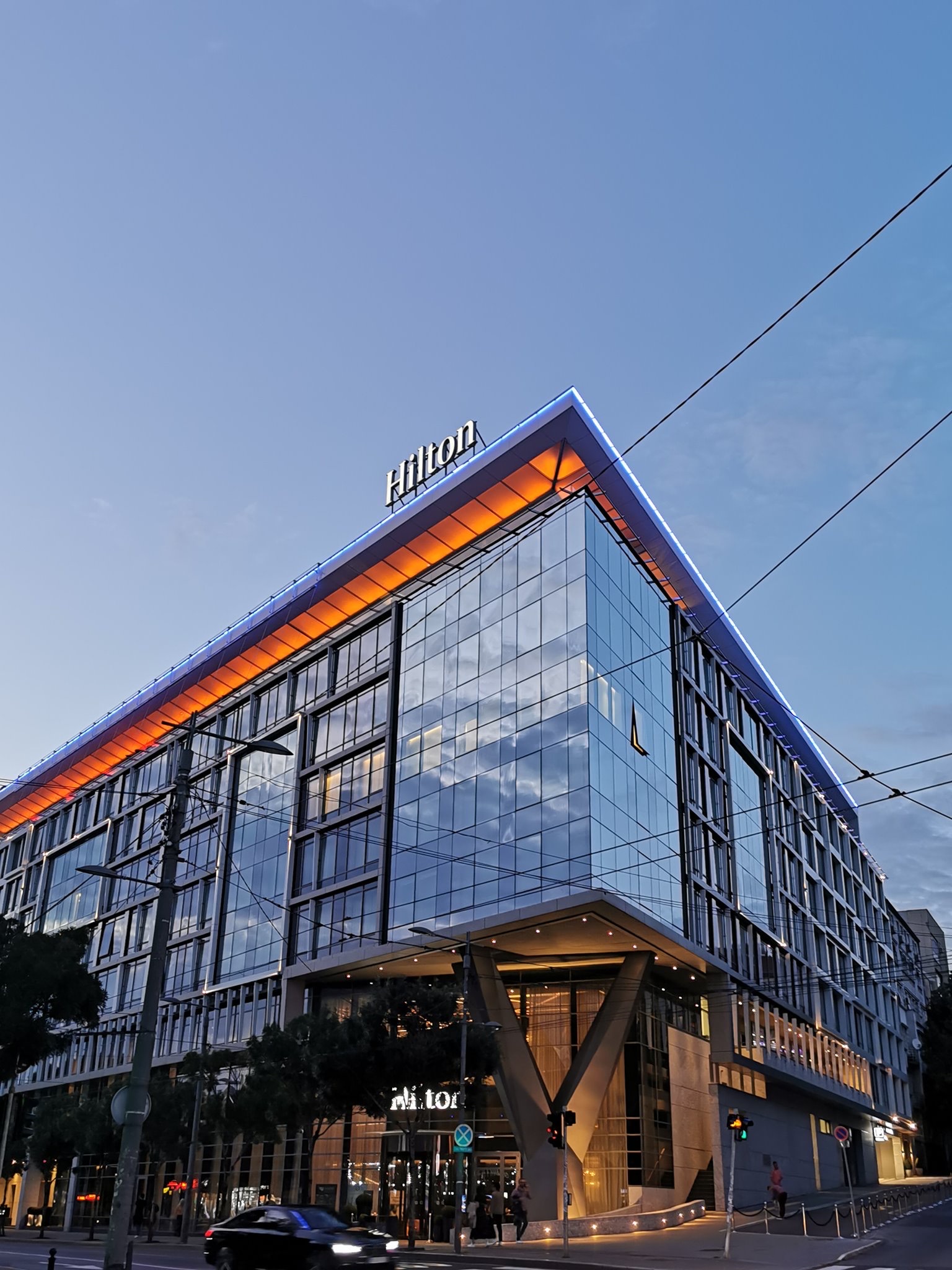 Hotel Hilton Beograd — osvetljeni ugao staklene fasade u sumrak