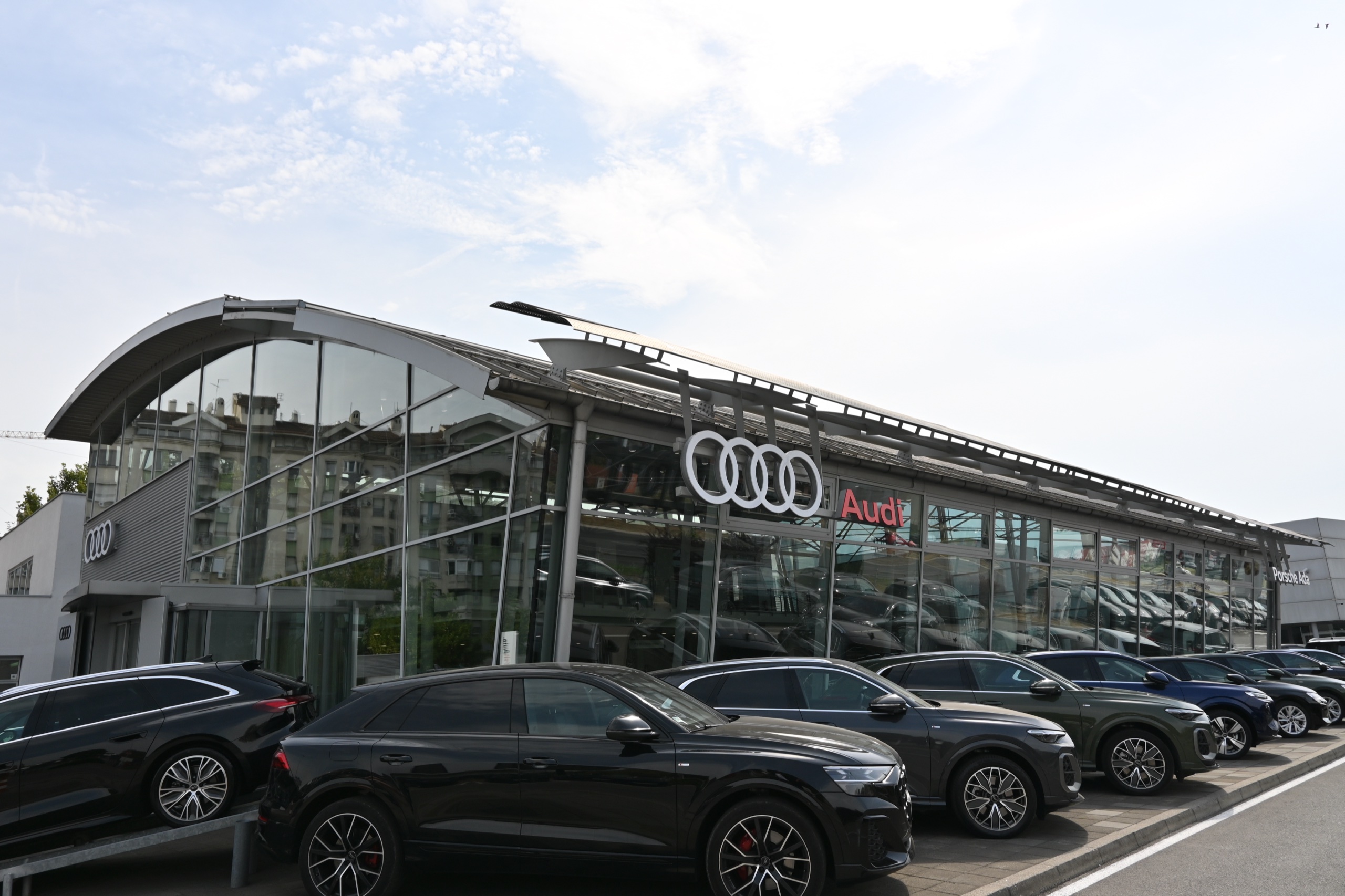 Auto salon Porsche Ada — Audi salon sa staklenom fasadom i nizom automobila ispred