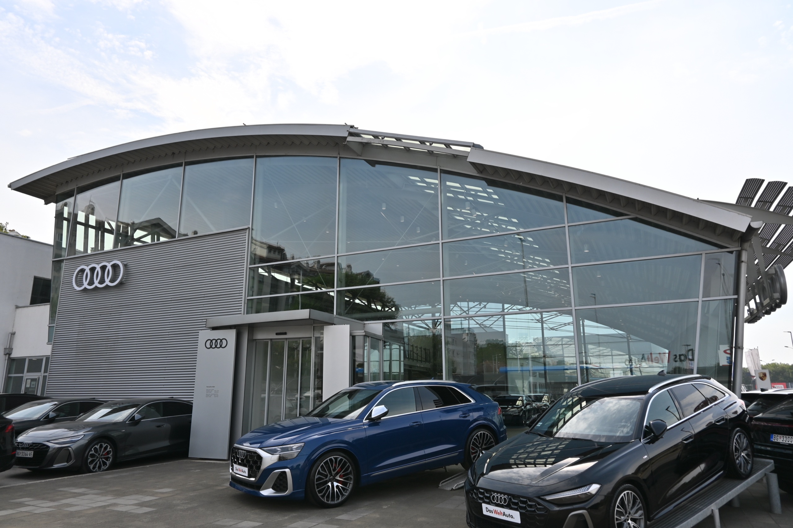 Auto salon Porsche Ada — čeona staklena fasada Audi salona pod zakrivljenim krovom