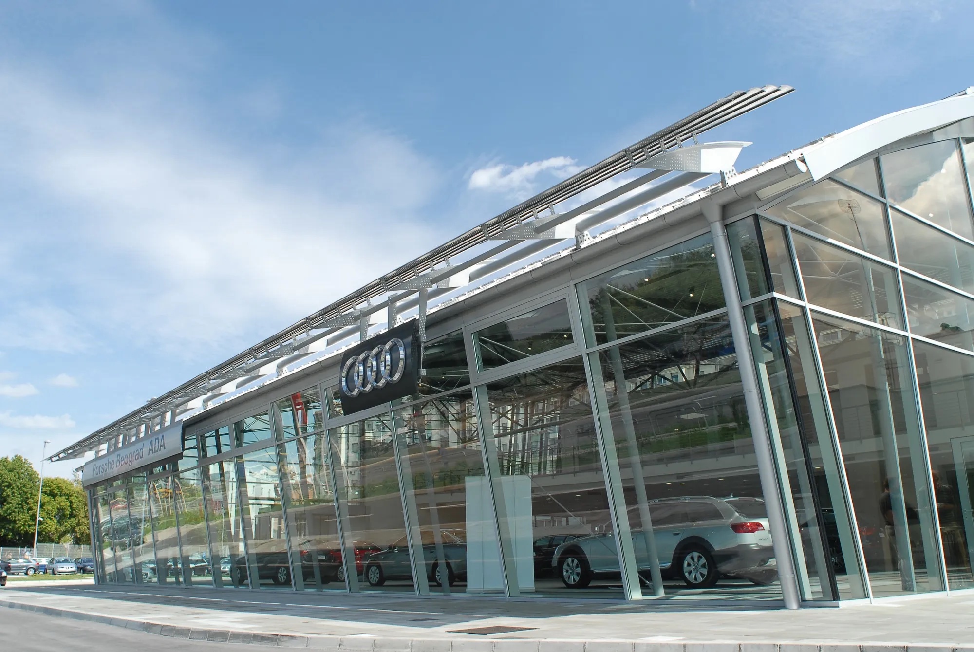 Auto salon Porsche Ada — staklena fasada Audi salona i nadstrešnica od lamela pod plavim nebom